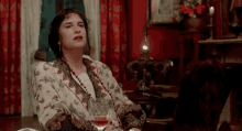 a woman sitting on a couch with a glass of wine in her hand