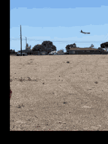 a plane is flying over a dry field