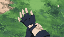 a person wearing a black glove is reaching out towards something in the grass