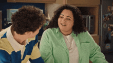 a woman in a green shirt talks to a man in a striped shirt