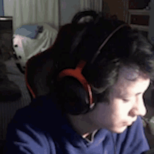 a man wearing headphones and a blue shirt looks down