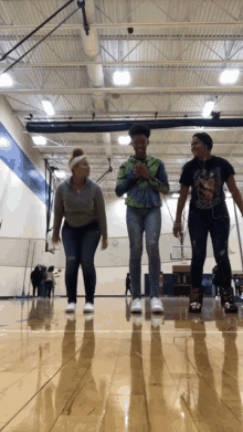 three girls rollerblading in a gym with one wearing a t-shirt that says ' nirvana ' on it