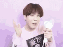a young man in a pink shirt is holding a light stick in his hand .