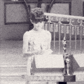 a woman in a white dress is standing in front of a podium with an oscar statue in the background