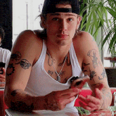 a man with a lot of tattoos on his arms is sitting at a table