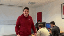 a man wearing a red puma hoodie stands in a room with other people