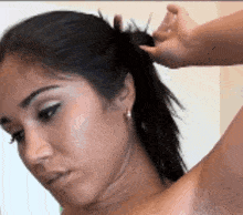 a woman 's hair is being pulled into a ponytail by a hand