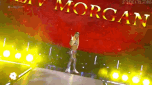 a woman is standing on a stage in front of a red background with the word morgan written on it .