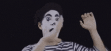 a man with a mime makeup on his face is making a hand gesture .
