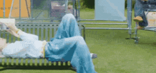 a person is laying on a bench in the grass .
