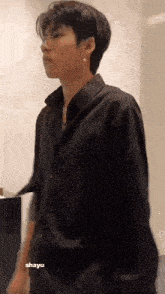 a young man is wearing a black shirt and earrings .