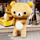 a stuffed teddy bear standing in front of a yellow box that says ' dalkuma ' on it