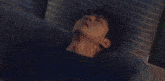 a man is laying on a bed with his head on a pillow
