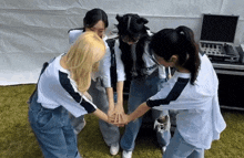a group of girls are putting their hands together in a circle with one wearing a shirt that says alone