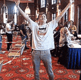 a man wearing a white shirt with a picture of a tiger on it is standing in a room with his arms outstretched