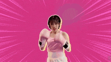a girl wearing pink boxing gloves is standing in front of a pink background