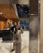 a man and a woman are posing for a photo in front of a mirror