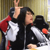 a woman wearing glasses and a black and white jacket is sitting in front of a akracing chair