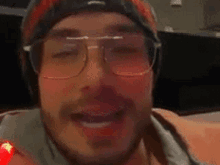 a close up of a man wearing glasses and a beanie .