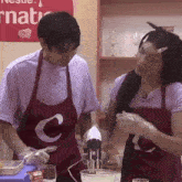 a man and a woman wearing red aprons with the letter c on it