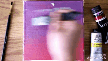 a bottle of winsor newton acrylic paint is on a wooden table