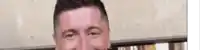 a close up of a man 's face with a blurred background and a smile on his face .