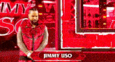 jimmy uso is standing in front of a red wall .