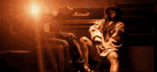 a woman sitting in front of a marshall amp