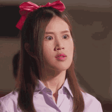 a woman with a pink bow in her hair is making a surprised face