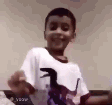 a young boy wearing a white shirt with a dinosaur on it is making a funny face .