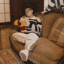 a man sitting on a couch wearing a headband that says ' supreme ' on it