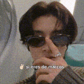 a man wearing sunglasses and a ring on his finger says si eres de marcos .
