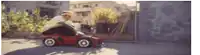 a man is riding a small red toy car on a street .