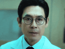 a man with glasses and a white coat looks at the camera