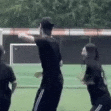 a man and two women are dancing on a soccer field .