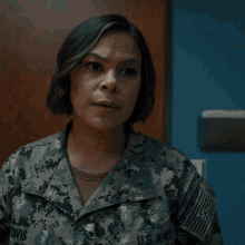 a woman in a camo uniform looks at the camera