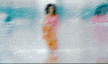 a woman in a pink top and orange pants is dancing in front of a screen that says buyutuldus.sabah.esp