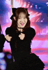 a girl in a black dress with a bow on her head is smiling