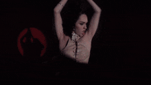 a woman in a corset is standing in the dark with her hands up
