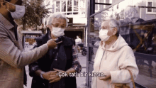 two older women wearing face masks are talking to a man