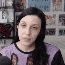 a woman wearing a purple shirt with a picture of a woman on it is sitting in front of a microphone .