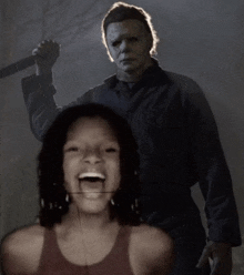 a man in a mask is holding a knife in front of a girl who is laughing