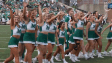 a group of cheerleaders in green and white uniforms with the letter m on them