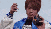 a young man in a blue and white jacket is holding a sword .