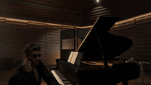 a man wearing sunglasses is sitting at a piano