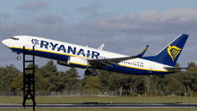 a blue and white ryanair plane is taking off from a runway