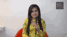 a woman in a yellow floral dress holds a microphone