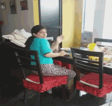 a woman in a blue shirt is sitting at a table with a plate of food