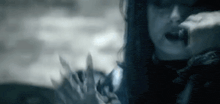 a black and white photo of a woman with long hair holding a knife in her hand .