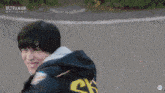 a man wearing a black hoodie with a yellow ck on the back